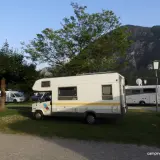 Kampery na kempingu, z widokiem na góry. Słońce zachodzi nad zatoką triesteńską, tworząc malowniczy krajobraz.
