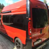Pomarańczowy Renault Trafic L2H2 z przyciemnianymi szybami stoi na podjeździe z kostki brukowej.