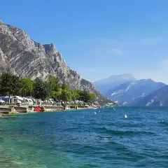 Kampery nad Jeziorem Garda, góry w tle, błękitna woda i słońce. Idealne miejsce na wakacje samochodem.