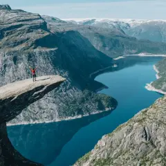Niesamowity punkt widokowy Norwegia. Człowiek na Trolltungę, z rękami w górze, podziwia fiord.