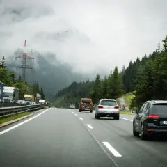 Jazda po autostradzie w Słowenii. Samochody i ciężarówki poruszają się po drodze w otoczeniu gór i lasów. Przepisy drogowe w Słowenii są przestrzegane.