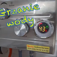Grzanie wody w przyczepie kempingowej. Cyfrowy wyświetlacz pokazuje 43°C. Pokrętła do regulacji temperatury i kontroli ognia.