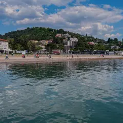 Spacerem po słonecznych plażach Słowenii, z widokiem na zielone wzgórza i błękitne morze.