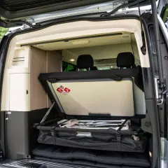 Wnętrze kampera Mercedes V Marco Polo z rozłożonym łóżkiem i schowkami.