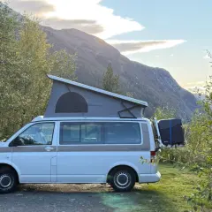 Kamper z podnoszonym dachem zaparkowany przy drodze w górach. Piękny widok na norweskie krajobrazy, idealne na podróż po **autostrady w Norwegii**.