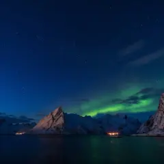 Zimowe krajobrazy Norwegii pod rozgwieżdżonym niebem i zorzą polarną. Idealny czas, kiedy najlepiej jechać do Norwegii, by zobaczyć to cudo.