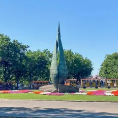 Rzeźba na Margit Sziget w Budapeszcie z kolorowymi kwiatami i turystycznymi pojazdami.