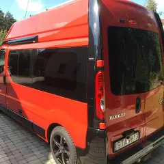 Pomarańczowy Renault Trafic L2H2 z przyciemnianymi szybami stoi na podjeździe z kostki brukowej.