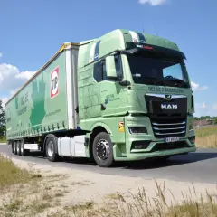 Zielona ciężarówka MAN z naczepą TIP na drodze. Długość zestawu c+e robi wrażenie, idealna do transportu.
