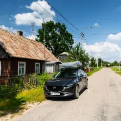 Czarny SUV z namiotem dachowym zaparkowany przy drewnianym domu, w drodze wzdłuż wschodniej granicy.