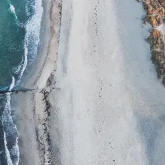 Puste plaże nad morzem, gdzie fale delikatnie muskają piasek, a wydmy porośnięte trawą tworzą naturalną granicę.