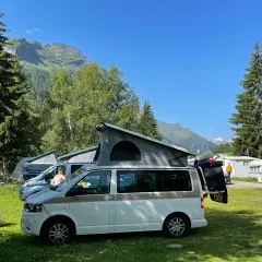 Kampery na kempingu w Austrii. W tle góry i lasy. Przepisy drogowe Austria są ważne dla bezpiecznej podróży.