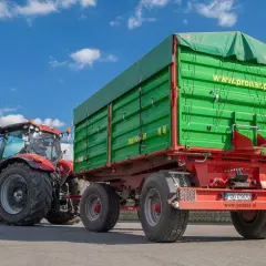 Czerwony traktor z zieloną przyczepą. Dowiedz się, jakich przyczep nie trzeba rejestrować, by sprawnie pracować w polu.
