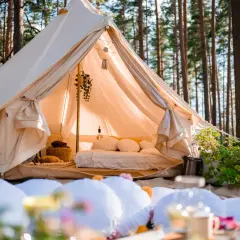 Wygodny namiot w lesie, z łóżkiem i dekoracjami, to właśnie glamping co to jest – luksusowy kemping.