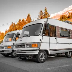 Dwa kampery Hymer stoją na tle gór i jesiennych drzew. Pamiętaj o opłatach drogowych Austria powyżej 3,5 tony.