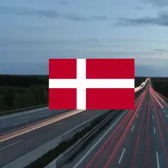 Autostrada nocą z widocznymi smugami świateł samochodów i flagą Danii. Winieta Danii na tle krajobrazu.