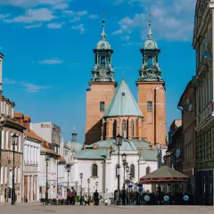 Rynek w Gnieźnie z katedrą w tle. Jasny, słoneczny dzień, błękitne niebo z chmurkami.
