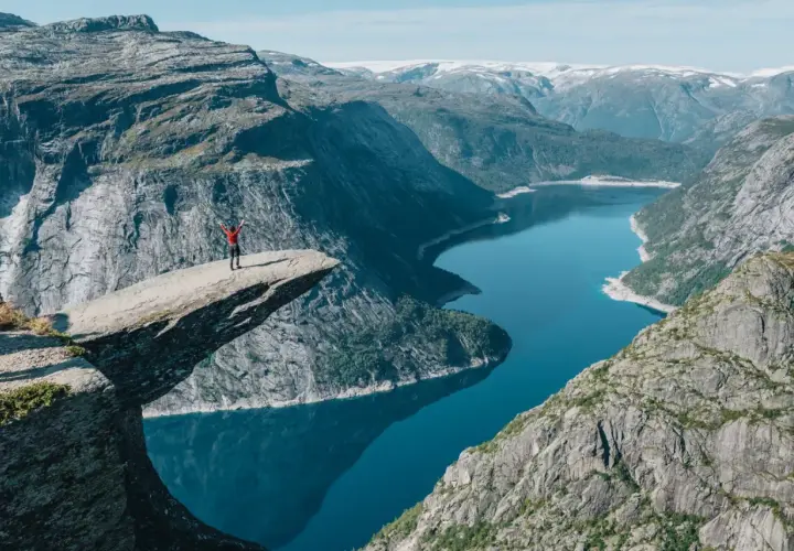 Niesamowity punkt widokowy Norwegia. Człowiek na Trolltungę, z rękami w górze, podziwia fiord.