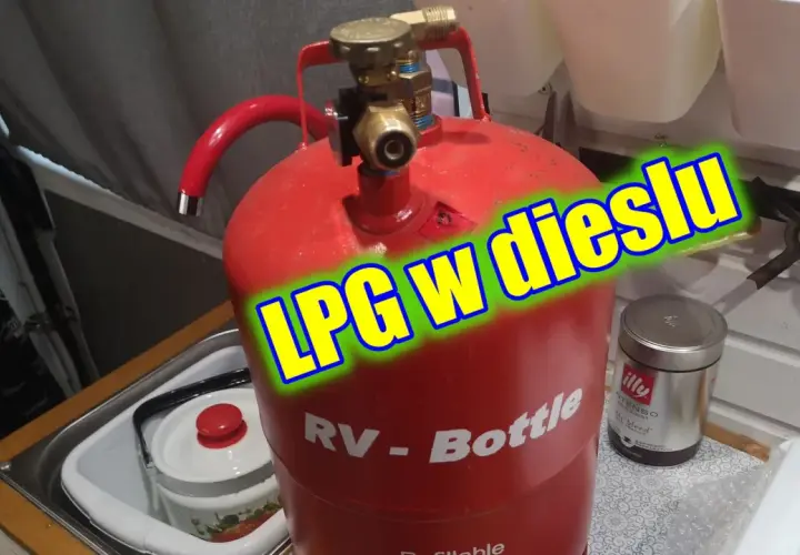 Czerwona butla gazowa RV-Bottle z zaworem, gotowa do tankowania LPG w dieslu. Obok puszka kawy Illy.