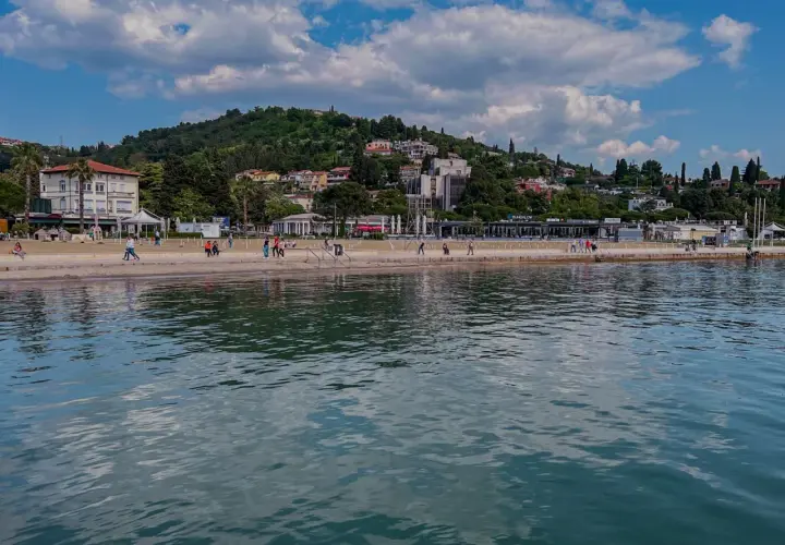 Spacerem po słonecznych plażach Słowenii, z widokiem na zielone wzgórza i błękitne morze.
