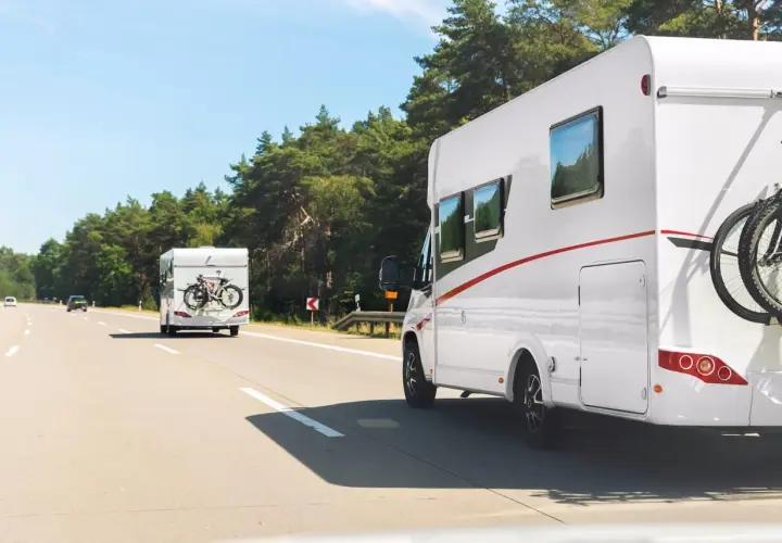 Dwa kampery jadą autostradą w Polsce. Na jednym z nich zamontowany jest bagażnik na rowery.