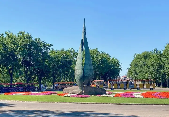 Rzeźba na Margit Sziget w Budapeszcie z kolorowymi kwiatami i turystycznymi pojazdami.