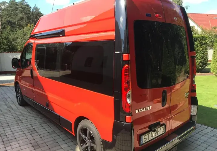 Pomarańczowy Renault Trafic L2H2 z przyciemnianymi szybami stoi na podjeździe z kostki brukowej.