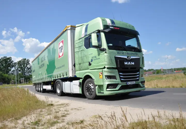 Zielona ciężarówka MAN z naczepą TIP na drodze. Długość zestawu c+e robi wrażenie, idealna do transportu.