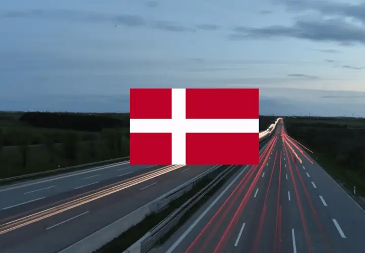 Autostrada nocą z widocznymi smugami świateł samochodów i flagą Danii. Winieta Danii na tle krajobrazu.