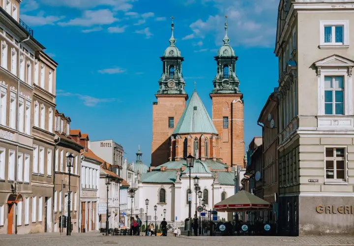Rynek w Gnieźnie z katedrą w tle. Jasny, słoneczny dzień, błękitne niebo z chmurkami.