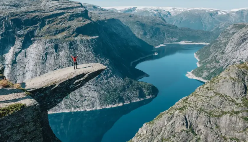 Niesamowity punkt widokowy Norwegia. Człowiek na Trolltungę, z rękami w górze, podziwia fiord.