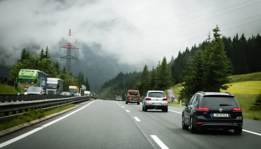 Jazda po autostradzie w Słowenii. Samochody i ciężarówki poruszają się po drodze w otoczeniu gór i lasów. Przepisy drogowe w Słowenii są przestrzegane.