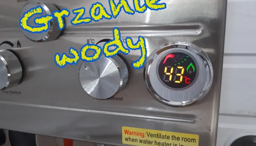 Grzanie wody w przyczepie kempingowej. Cyfrowy wyświetlacz pokazuje 43°C. Pokrętła do regulacji temperatury i kontroli ognia.