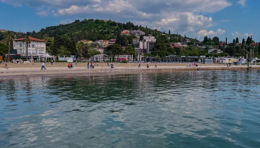 Spacerem po słonecznych plażach Słowenii, z widokiem na zielone wzgórza i błękitne morze.