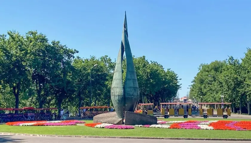 Rzeźba na Margit Sziget w Budapeszcie z kolorowymi kwiatami i turystycznymi pojazdami.