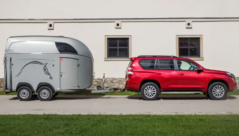 Czerwony SUV holuje przyczepę z koniem. B+E co daje? Możliwość przewiezienia ukochanego zwierzęcia na zawody.
