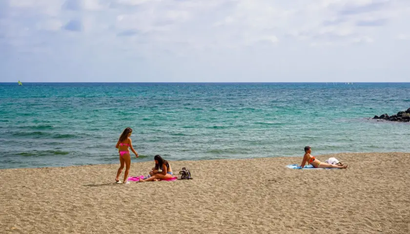 Trzy kobiety relaksują się na piaszczystych plażach Ostii. W tle błękitne morze i kilka żaglówek.