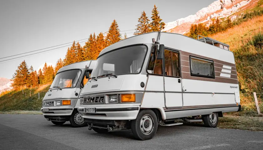 Dwa kampery Hymer stoją na tle gór i jesiennych drzew. Pamiętaj o opłatach drogowych Austria powyżej 3,5 tony.