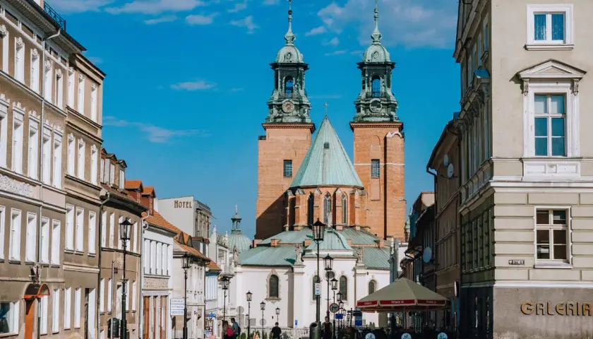 Rynek w Gnieźnie z katedrą w tle. Jasny, słoneczny dzień, błękitne niebo z chmurkami.