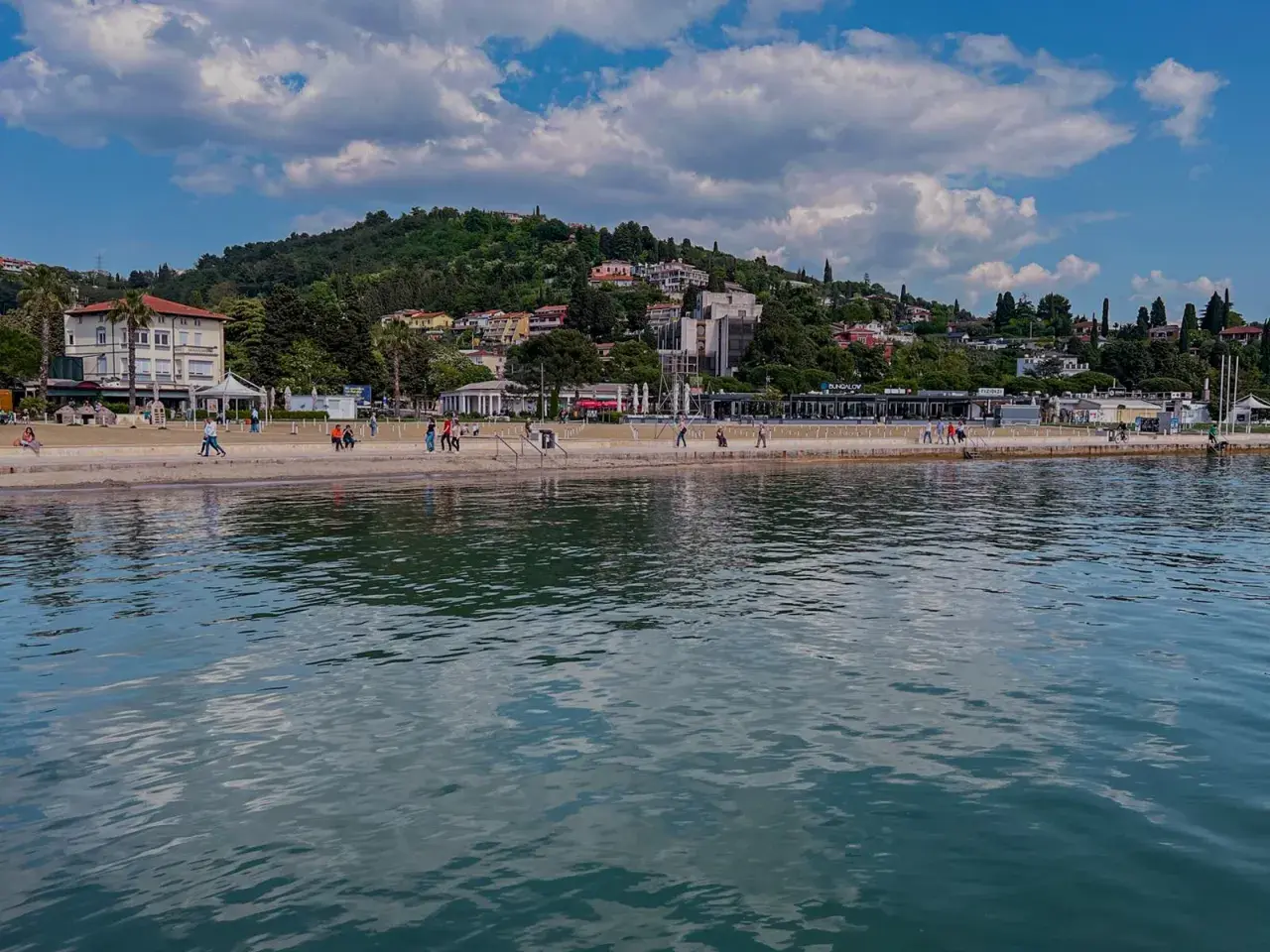Spacerem po słonecznych plażach Słowenii, z widokiem na zielone wzgórza i błękitne morze.
