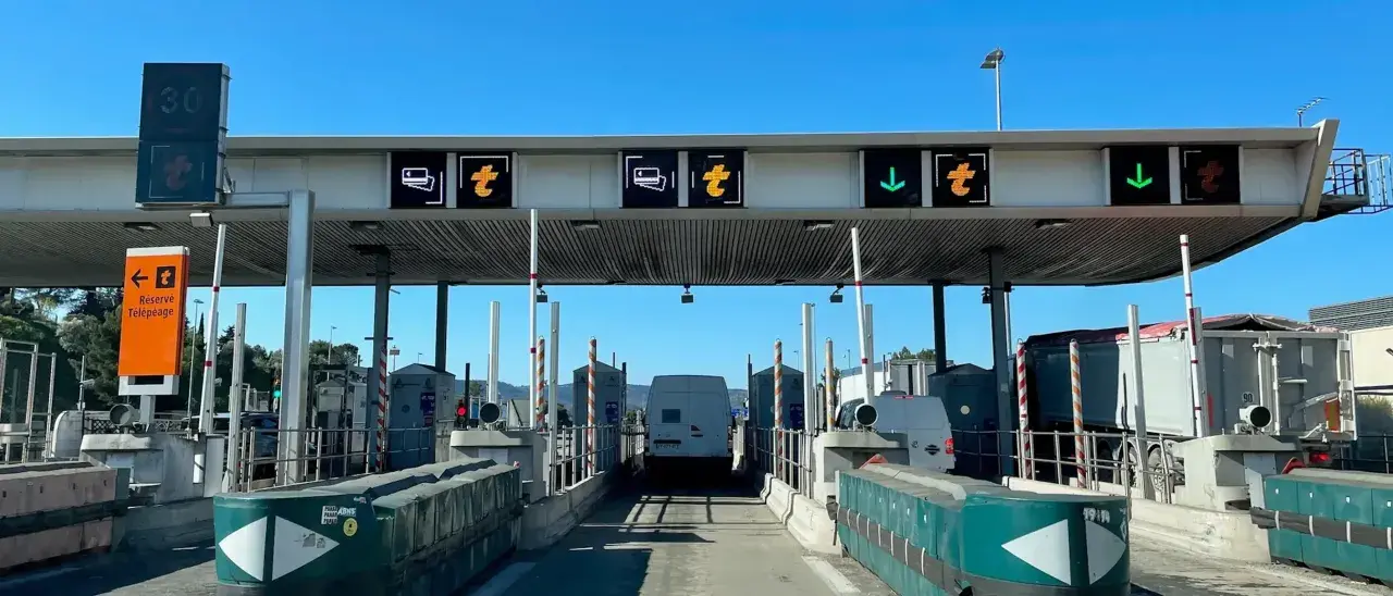 Francuskie winiety na autostradzie. Znaki informują o pasach do płatności, ograniczeniu prędkości do 30 km/h i kierunku jazdy.