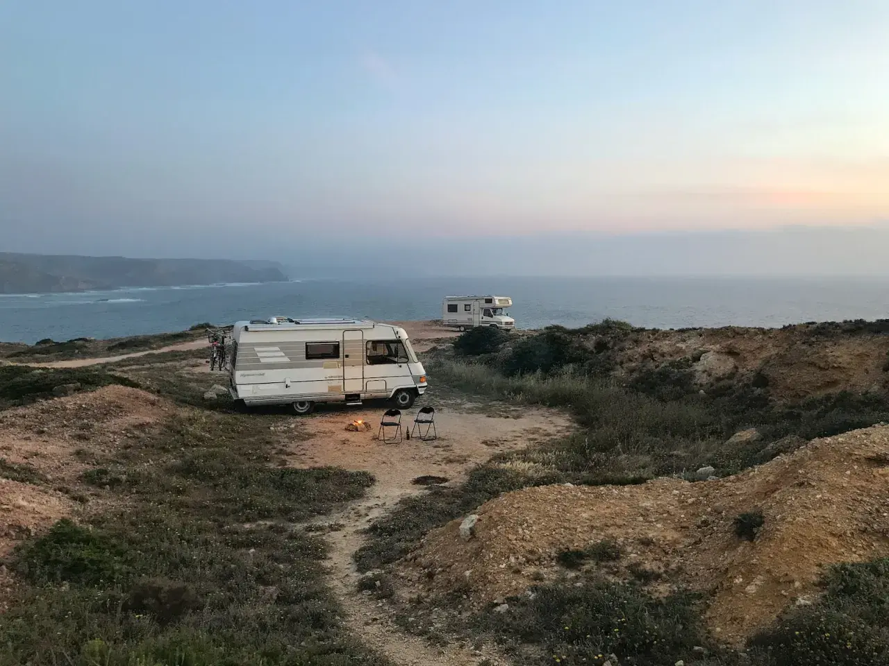 Dwa kampery na klifie nad oceanem. Ognisko i krzesła czekają na wieczór. To nie jest parkowanie w Berlinie, ale idealne miejsce na nocleg.