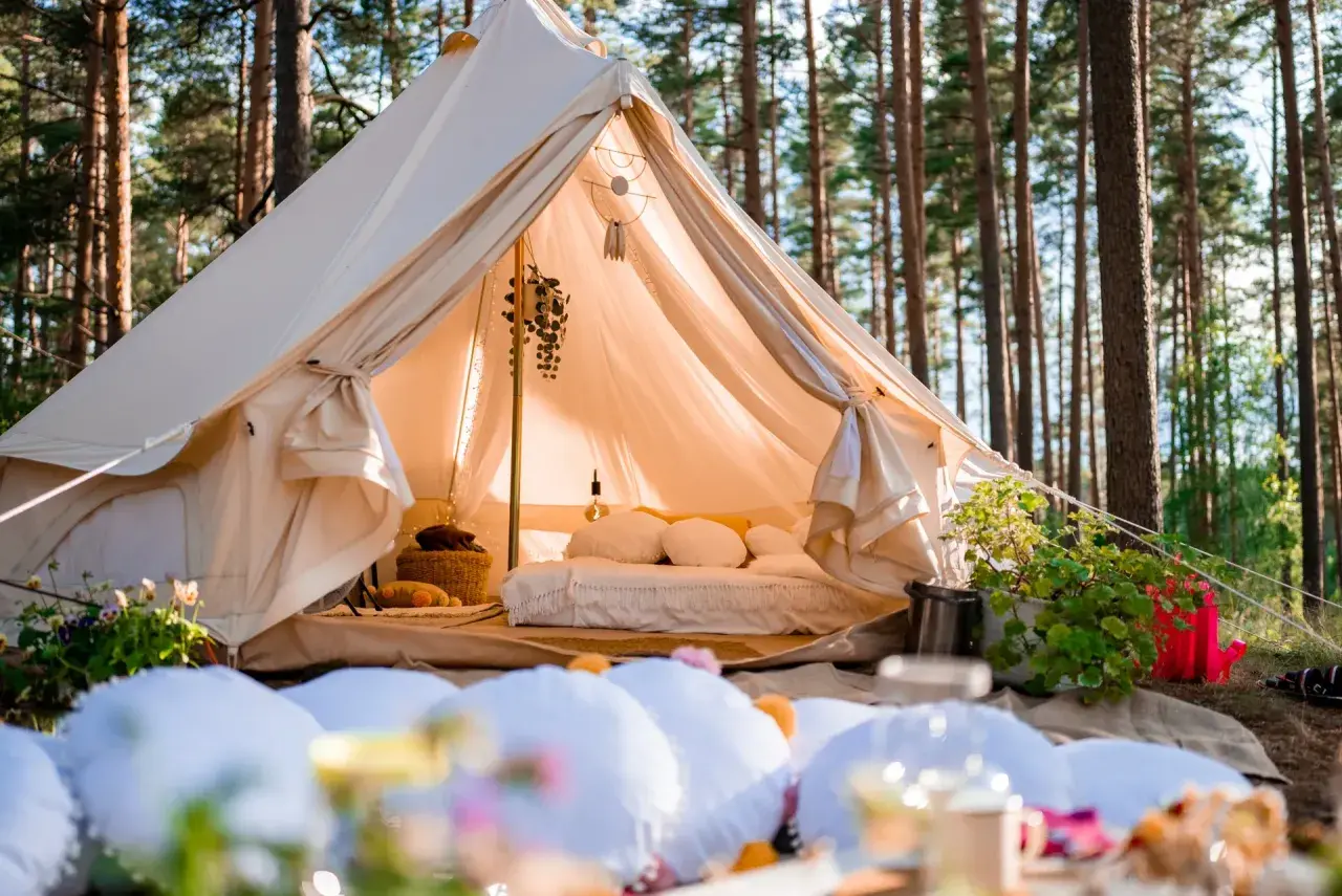 Wygodny namiot w lesie, z łóżkiem i dekoracjami, to właśnie glamping co to jest – luksusowy kemping.