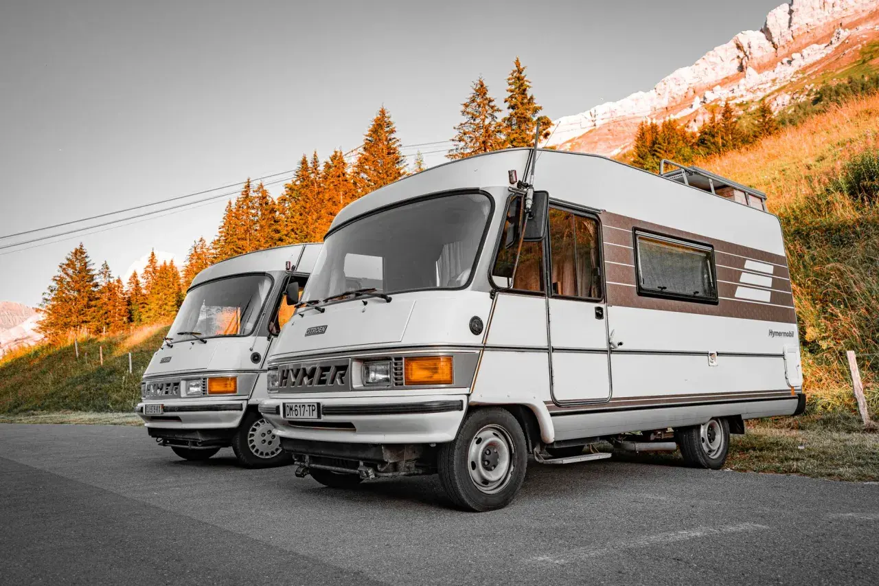 Dwa kampery Hymer stoją na tle gór i jesiennych drzew. Pamiętaj o opłatach drogowych Austria powyżej 3,5 tony.
