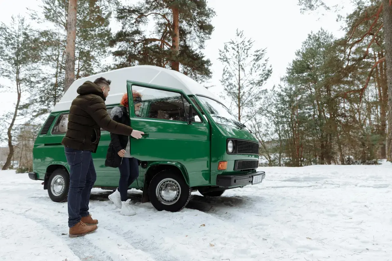 Para, otwierając drzwi zielonego kampera, zastanawia się, czy kamper jest samochodem osobowym. Zimowy las i śnieg wokół.