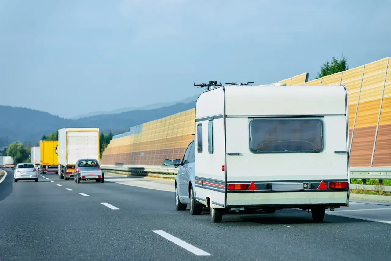 Kempingowy samochód i ciężarówki jadące z dużą prędkością na drodze dwujezdniowej.