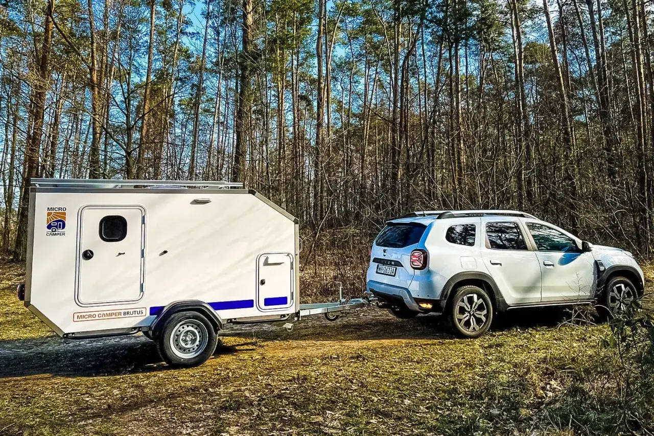 Dacia Duster z przyczepą Micro Camper Brutus gotowa na leśną przygodę. DMC przyczepy pozwala na łatwe manewrowanie.