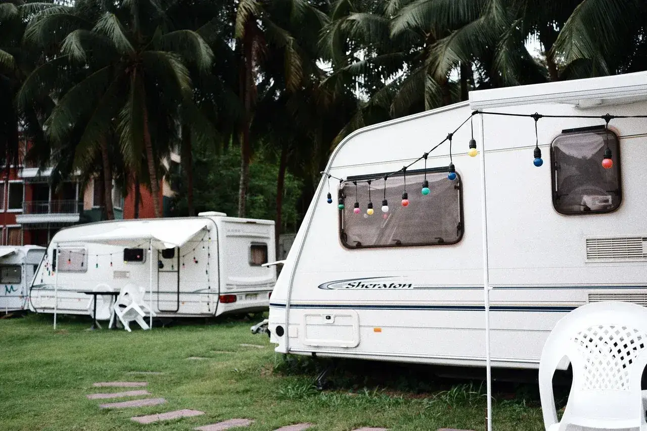 Kemping pod palmami, przyczepy kempingowe ozdobione kolorowymi lampkami. Marzenie o podróżach z przyczepą, czyli prawo jazdy na przyczepę, staje się rzeczywistością.