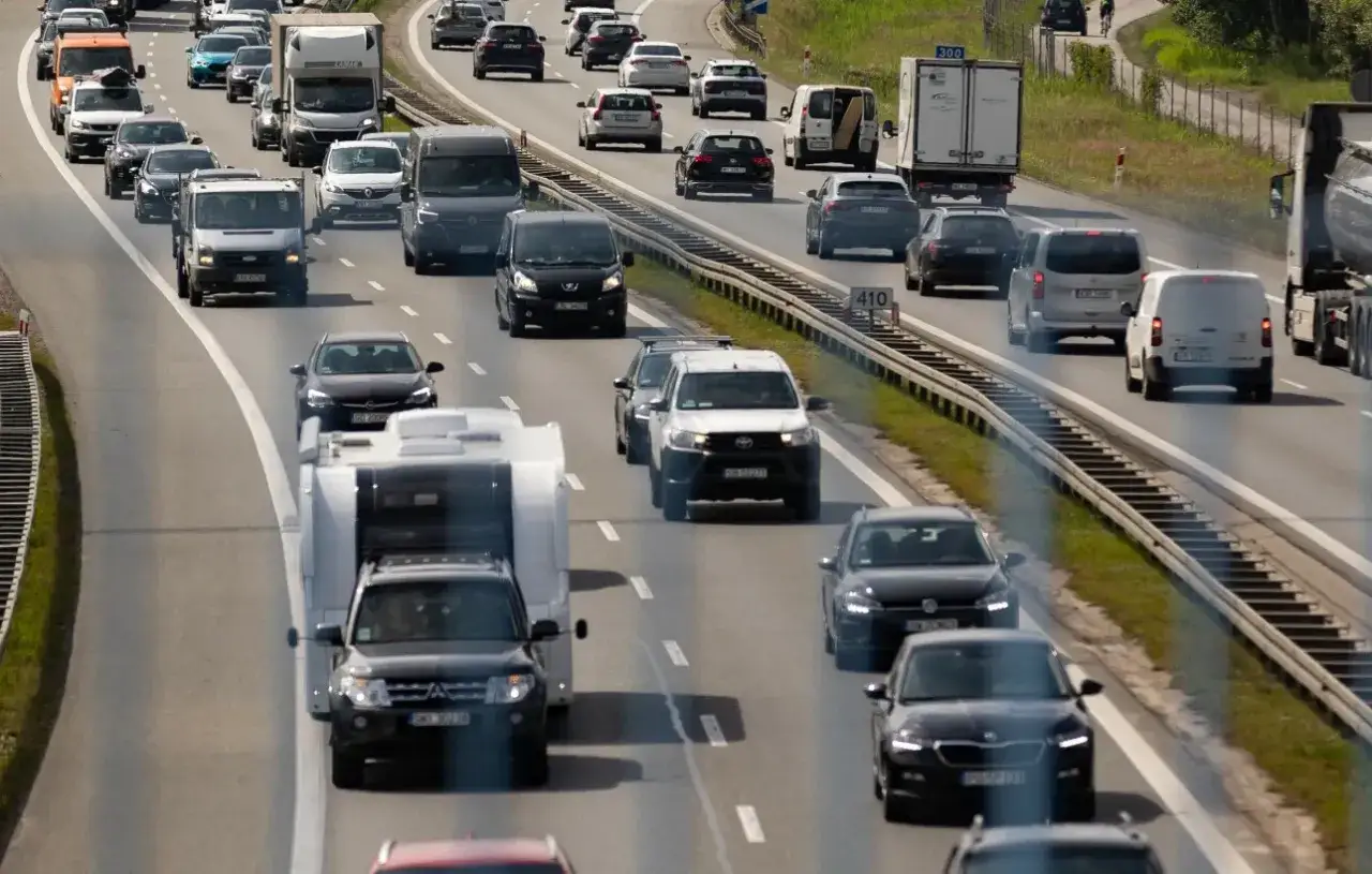 Jazda z przyczepą po autostradzie. Samochód z przyczepą kempingową porusza się w ruchu drogowym wśród innych pojazdów.